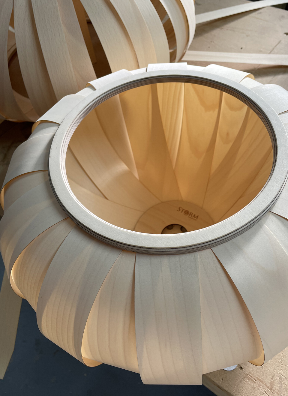 Handmade baby pumpkin pendant light sitting upside down on a bench to show the internal structure of sycamore veneer leaves.
